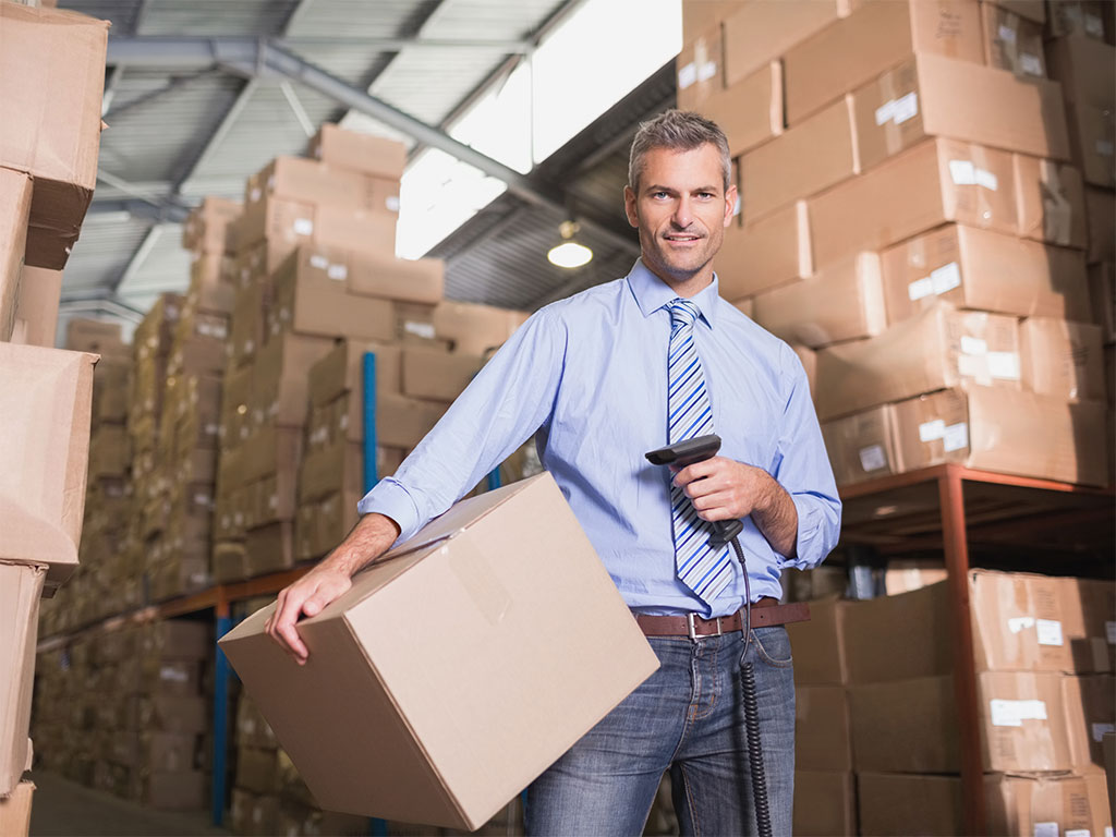 A man holding a box to scan in a storage warehouse of a moving company in Dubai